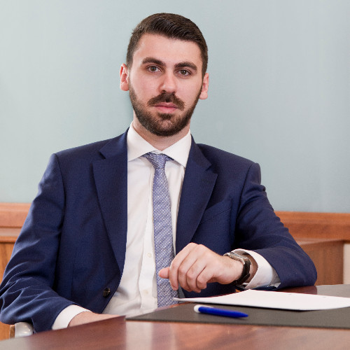 Chris Agius sitting at a desk in a suit