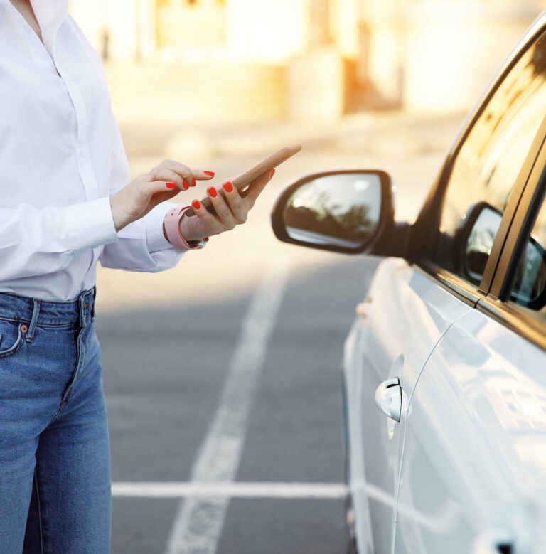 woman with phone next to vehicle