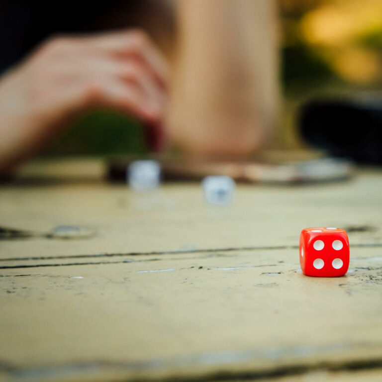 table with red die in the front and white dice blurred in the back