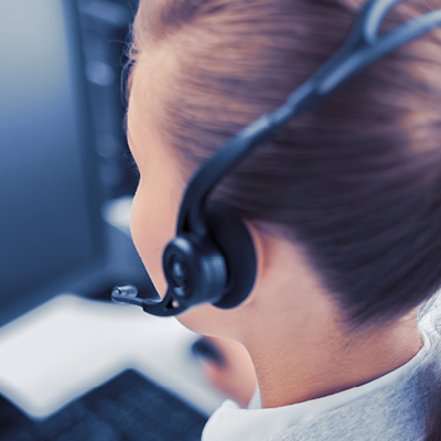 woman with headset on staring at a computer screen