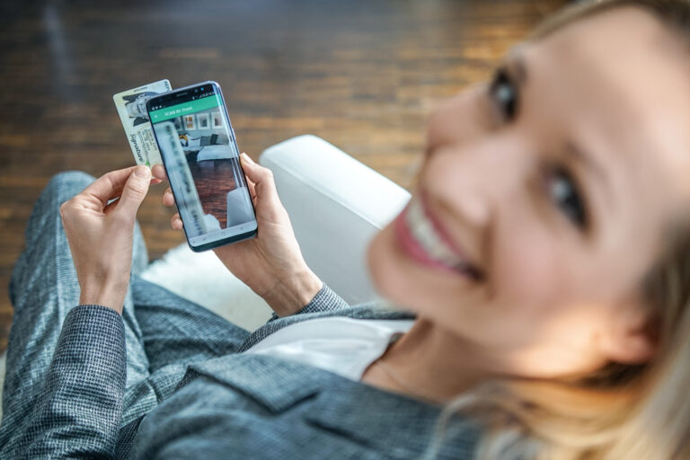 woman looking at the camera smiling holding a phone taking a photo of her ID