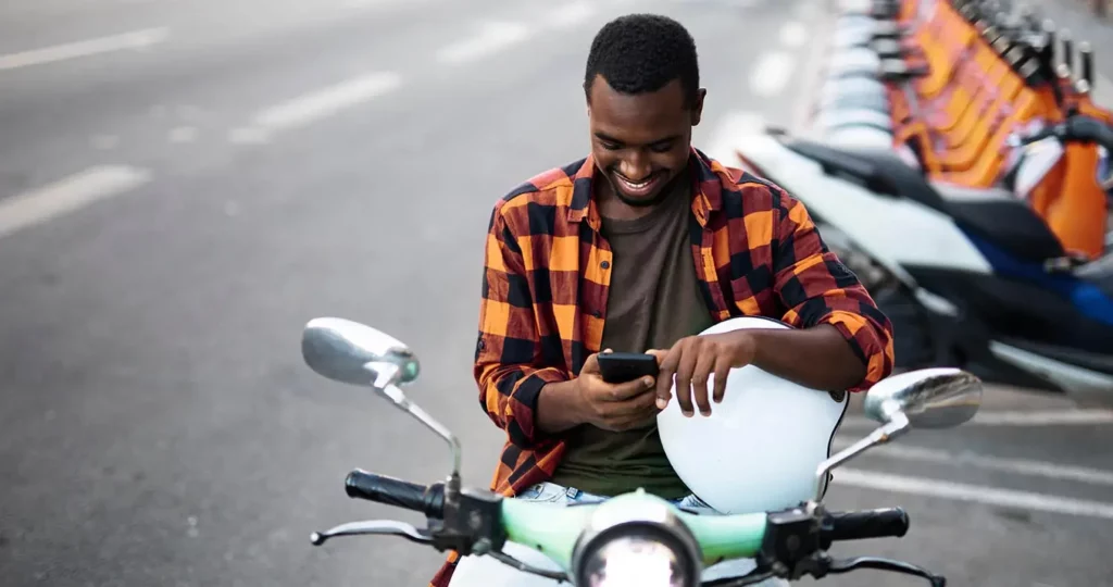 man sitting on an escooter looking at his phone